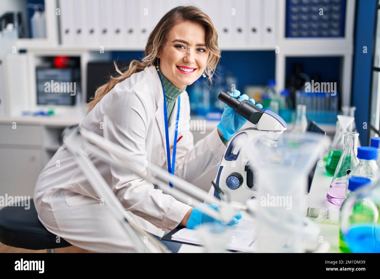 Una joven científica que utiliza un informe de redacción al microscopio en  el laboratorio Fotografía de stock - Alamy