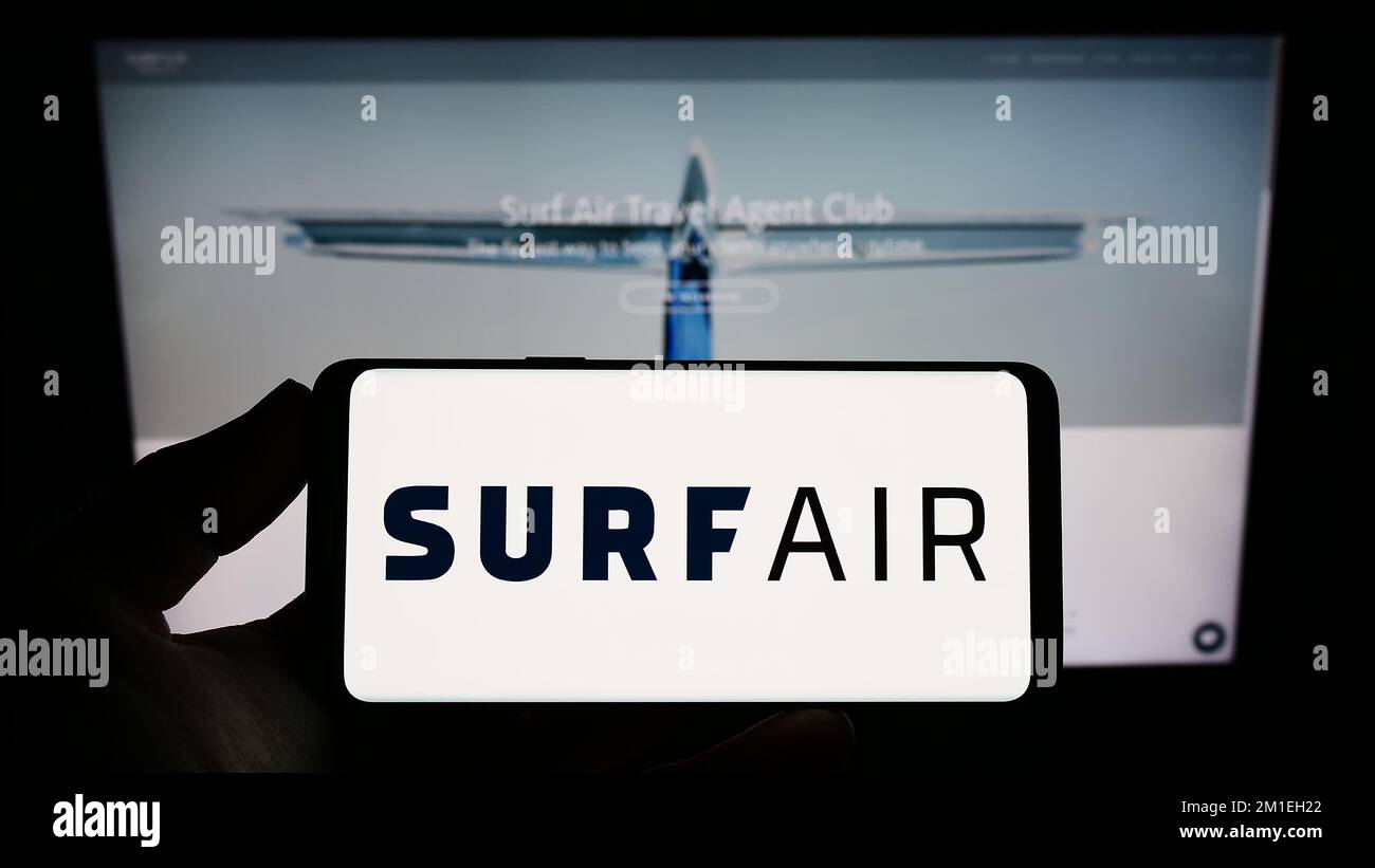 Persona que sostiene el smartphone con el logotipo de la compañía de aviación de EE.UU. Surf Air Mobility en la pantalla delante del sitio web. Enfoque la pantalla del teléfono. Foto de stock