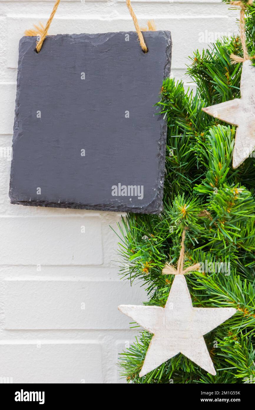 Letrero de pizarra vacío con espacio de copia junto a una corona de Navidad con estrellas Foto de stock