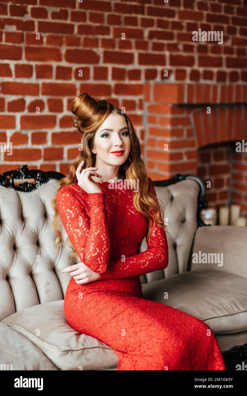 niña con pelo rojo en un vestido rojo brillante en una habitación luminosa en sofá antiguo Fotografía de stock - Alamy