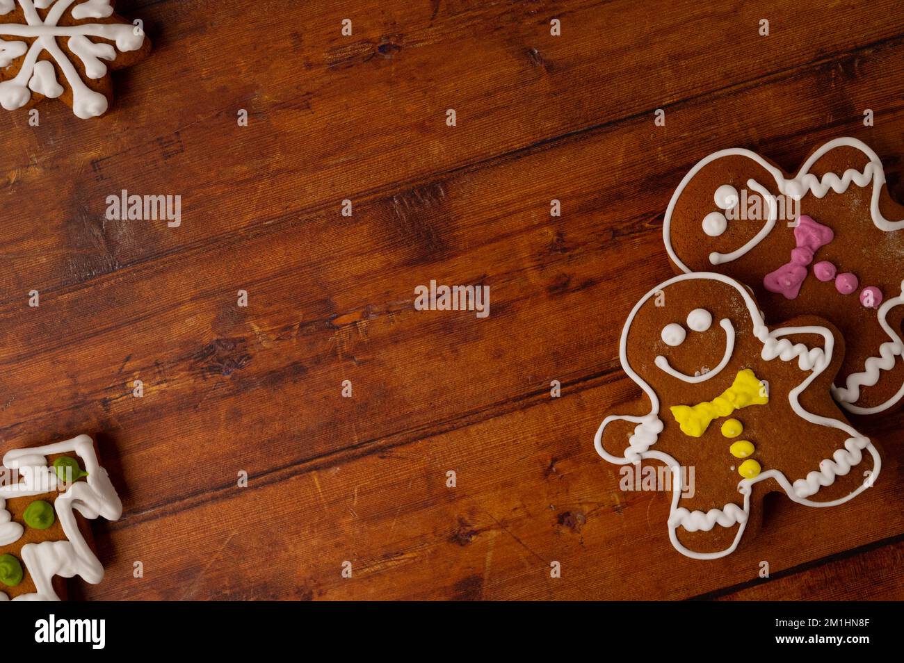 Hombres de pan de jengibre con glaseado de colores sobre una mesa de madera marrón con varias gingerbreads en las esquinas. Espacio de copia. Vista superior. Foto de stock