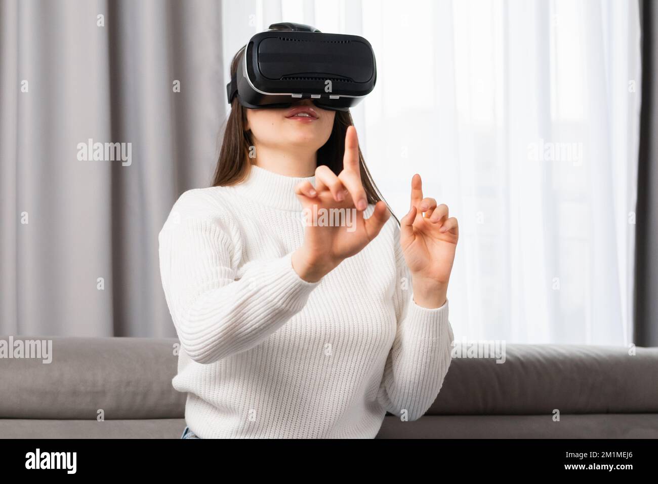 Una hermosa adolescente interactúa con la realidad virtual y toca una  interfaz invisible sentada en la caja fuerte del salón Fotografía de stock  - Alamy