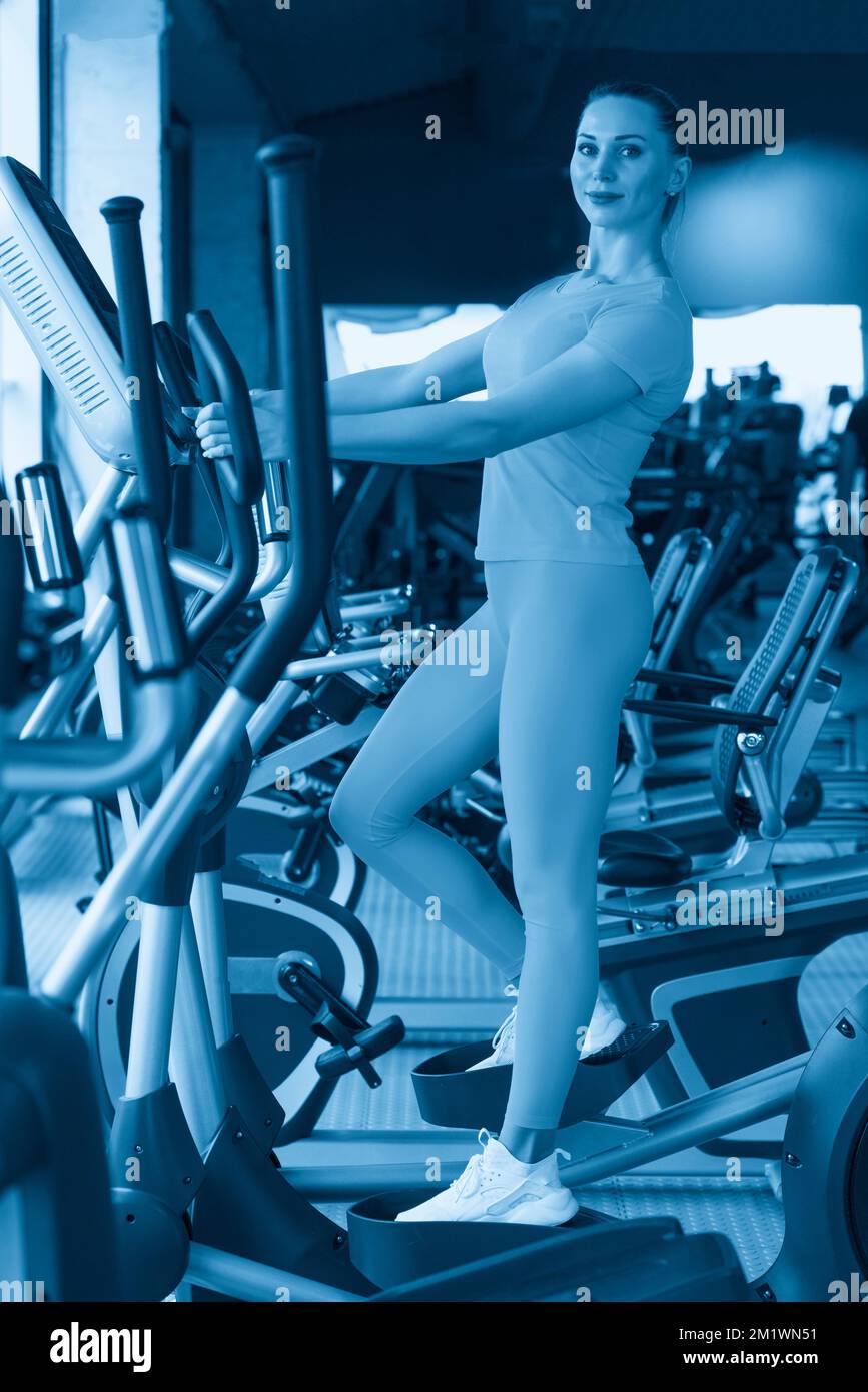 Mujer joven de pie en una máquina elíptica en el gimnasio Fotografía de  stock - Alamy