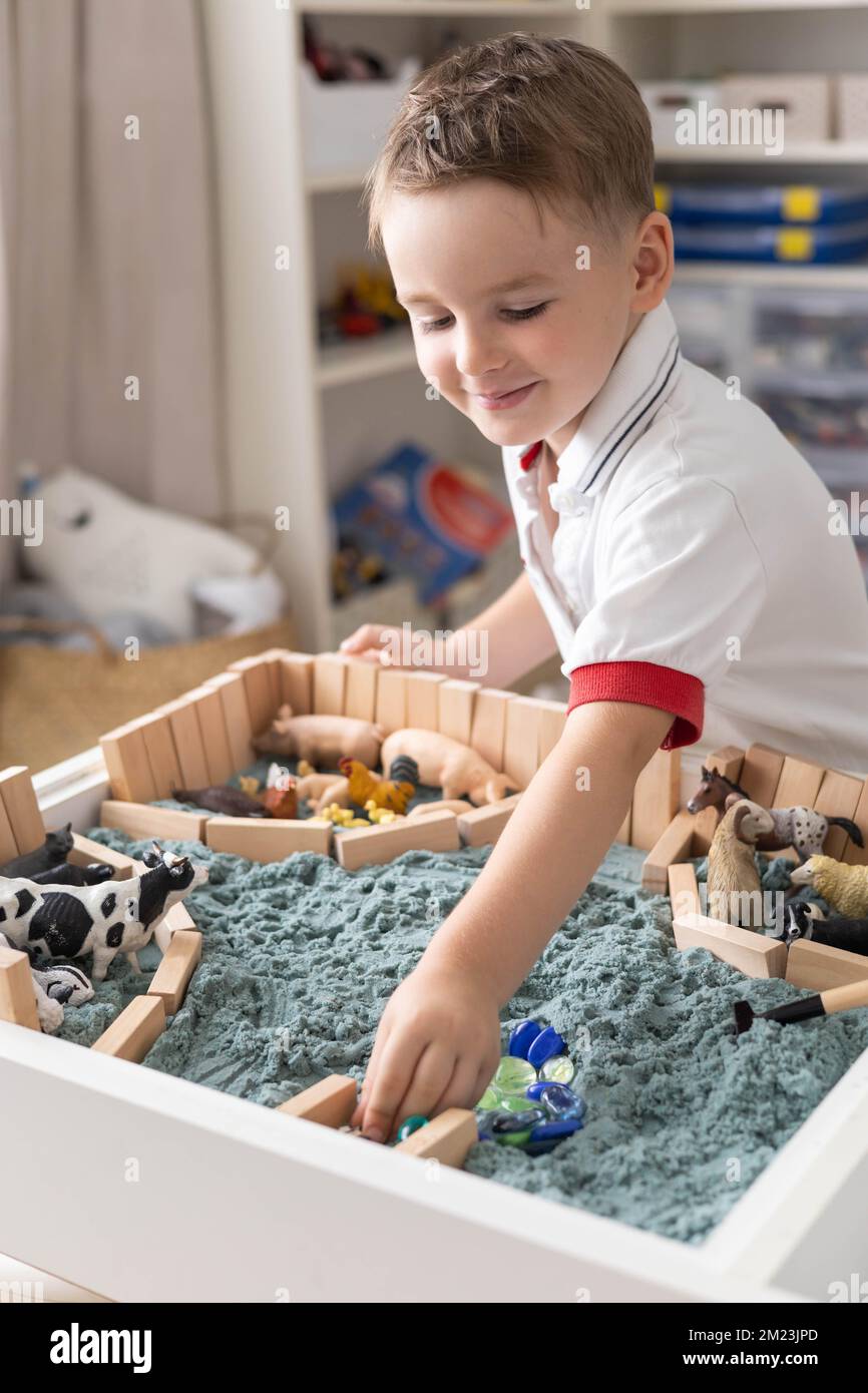 Lindo bebé niño jugando caja sensorial mesa de arena cinética con animales  de granja Fotografía de stock - Alamy