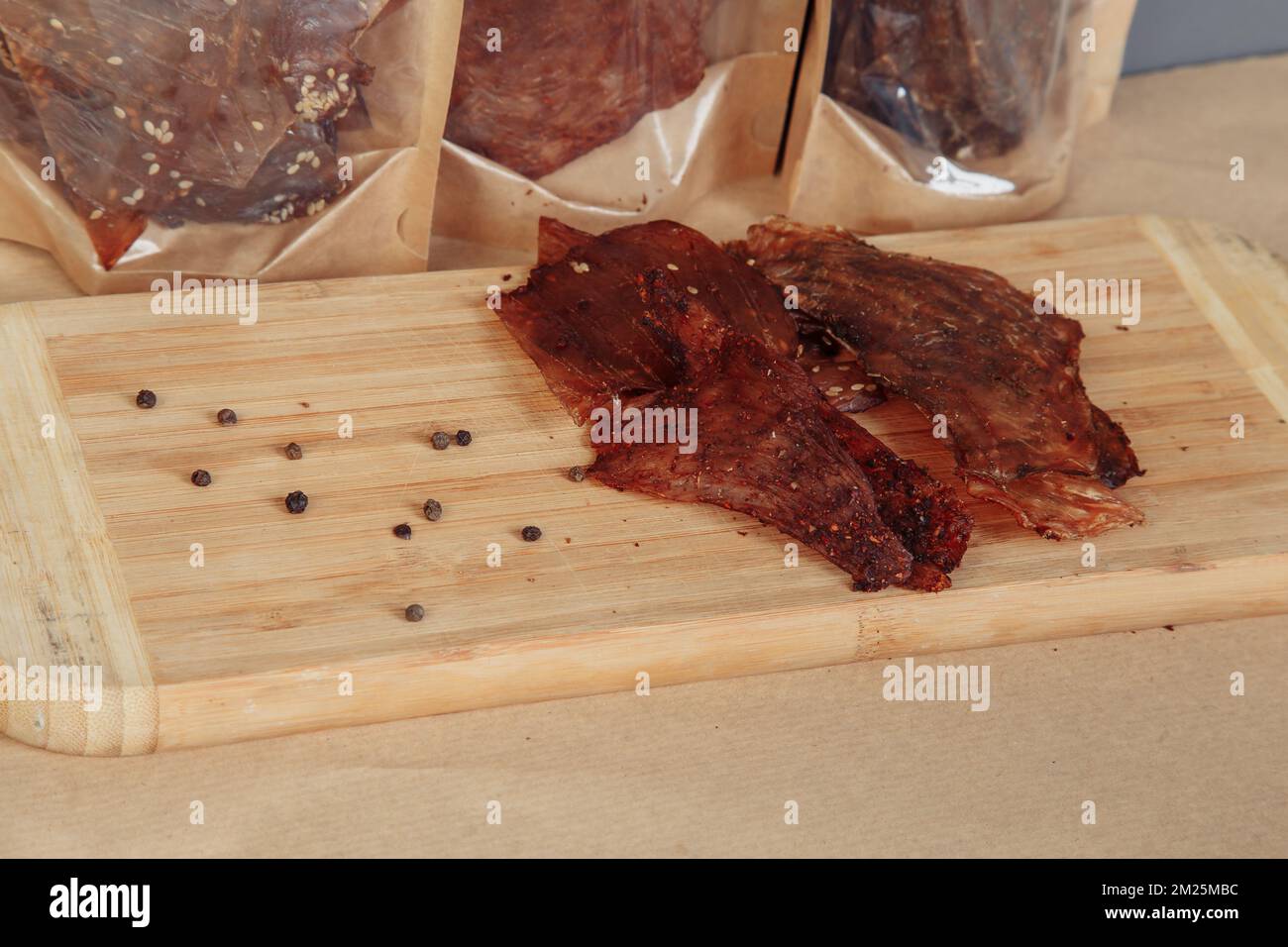 Algunas cajas de cartón artesanal con golosinas deshidratadas, la más alta se abre, llena de sabores crujientes de carne seca de ternera y pollo. Mascota casera Foto de stock