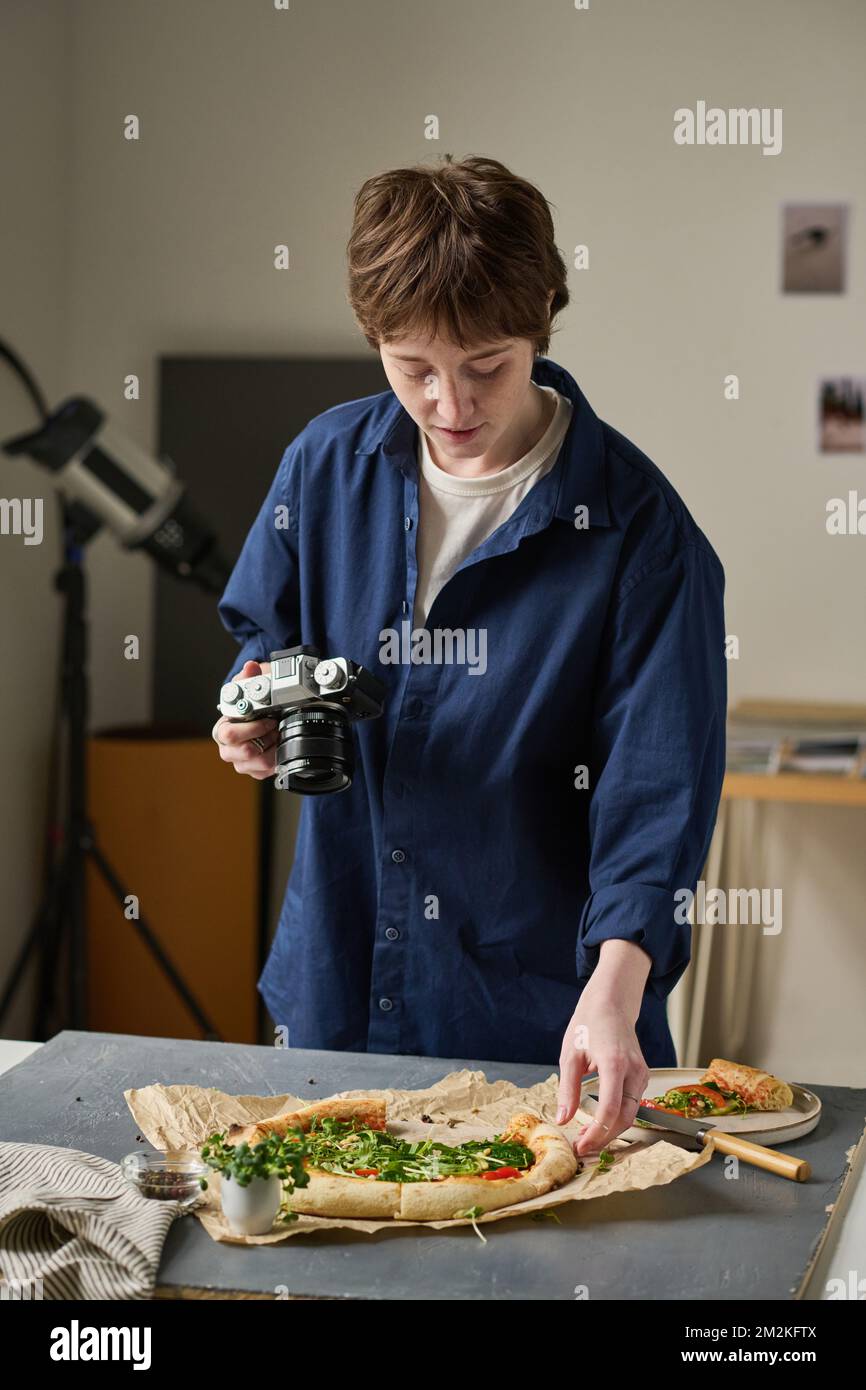 Fotógrafo profesional joven que dispara la pizza en el estudio para el blog de la comida Foto de stock