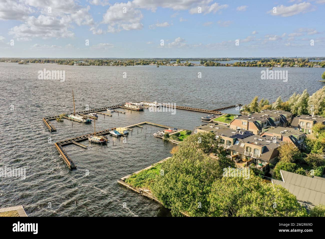 algunos barcos en el agua y casas en el otro lado del lago, con nubes sobre ellos para que parezca Foto de stock