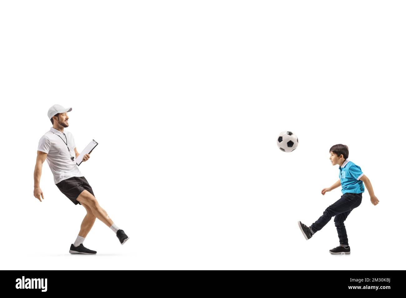 Entrenador de fútbol patea una pelota con un niño aislado sobre fondo blanco Foto de stock