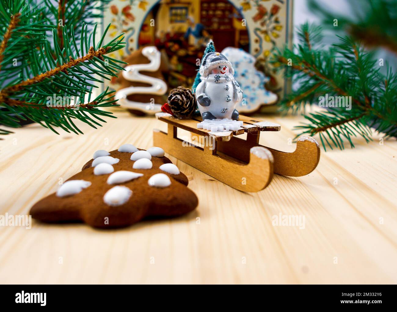 Muñeco de nieve en un trineo, decoración festiva, galletas, ramas de árbol de Navidad verde Foto de stock