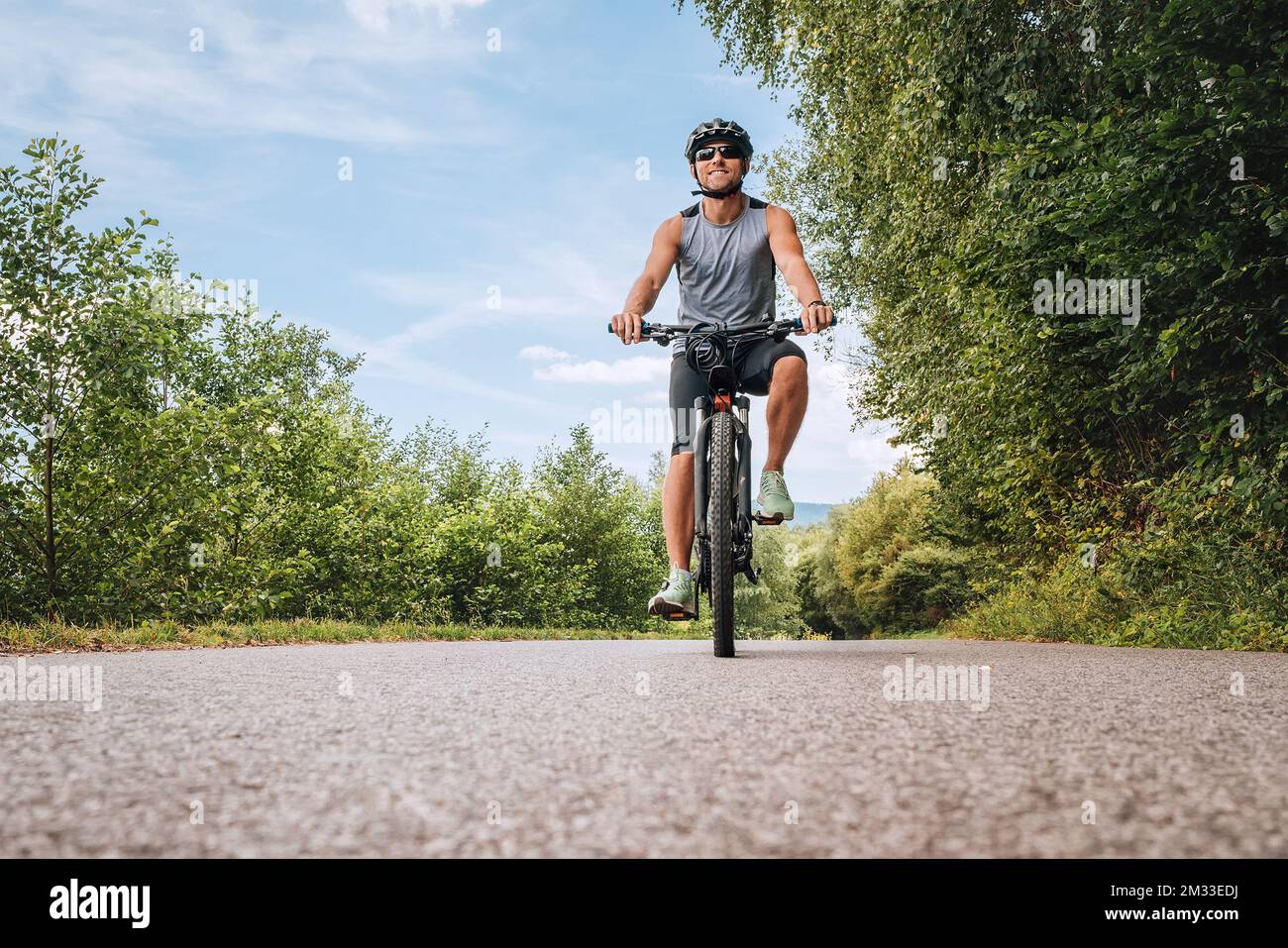 Posando Para Una Cámara Ciclista En Bicicleta Está En La Carretera De  Asfalto En El Bosque En El Día Soleado Imagen de archivo - Imagen de casco,  afuera: 166416277