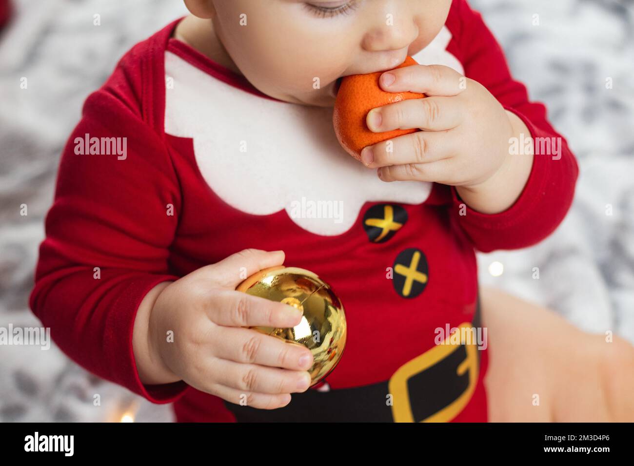 bebé de año nuevo en traje de santa con mandarinas Foto de stock