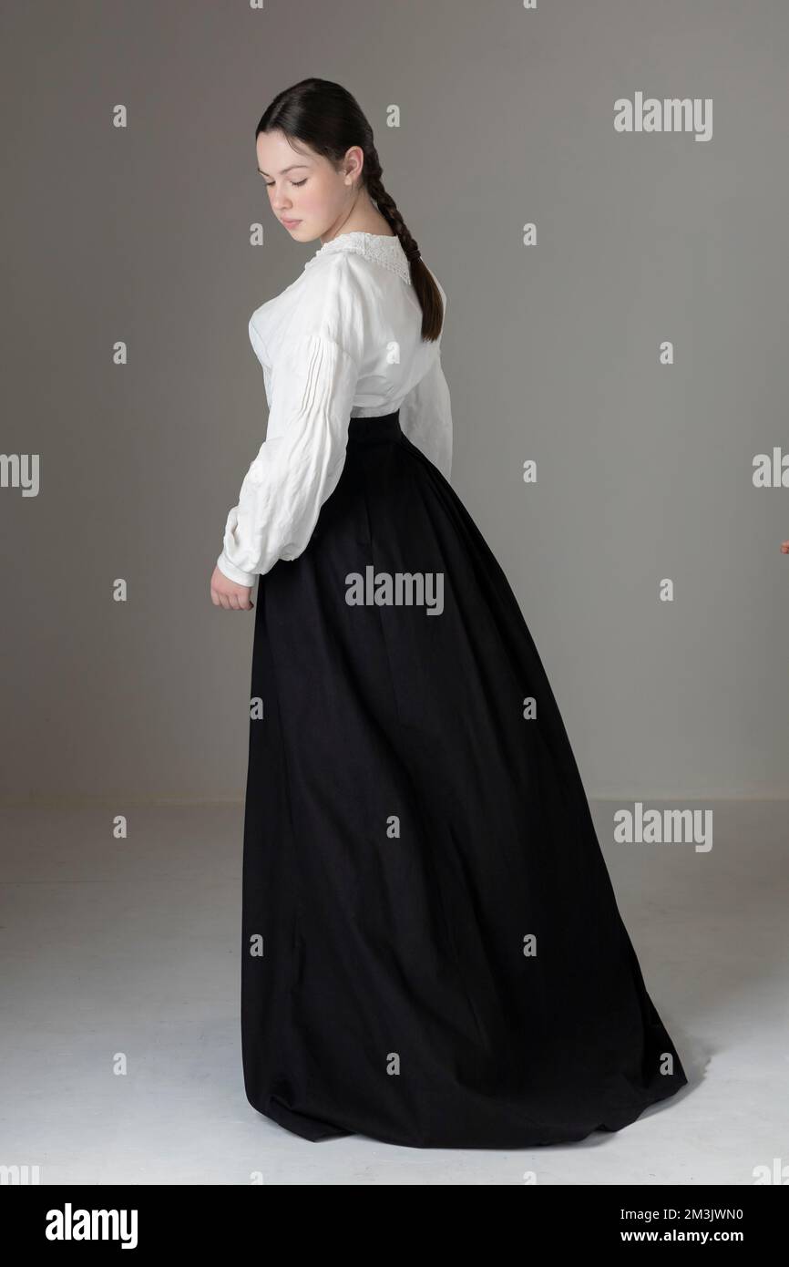 Una joven mujer victoriana o eduardiana con una blusa Garibaldi de lino  blanco y una falda negra y de pie solo contra un fondo de estudio  Fotografía de stock - Alamy