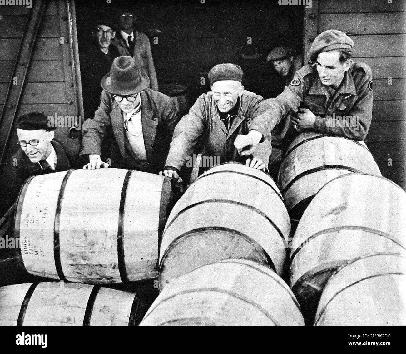 Un grupo de trabajadores alemanes descargando barriles de leche en polvo de un camión británico, bajo la supervisión de un soldado británico, Berlín, agosto de 1945. Al final de la Segunda Guerra Mundial en Europa había una gran escasez de alimentos y las fuerzas británicas tuvieron que traer en grandes cantidades a una población hambrienta de Berlín. Fecha: 1945 Foto de stock