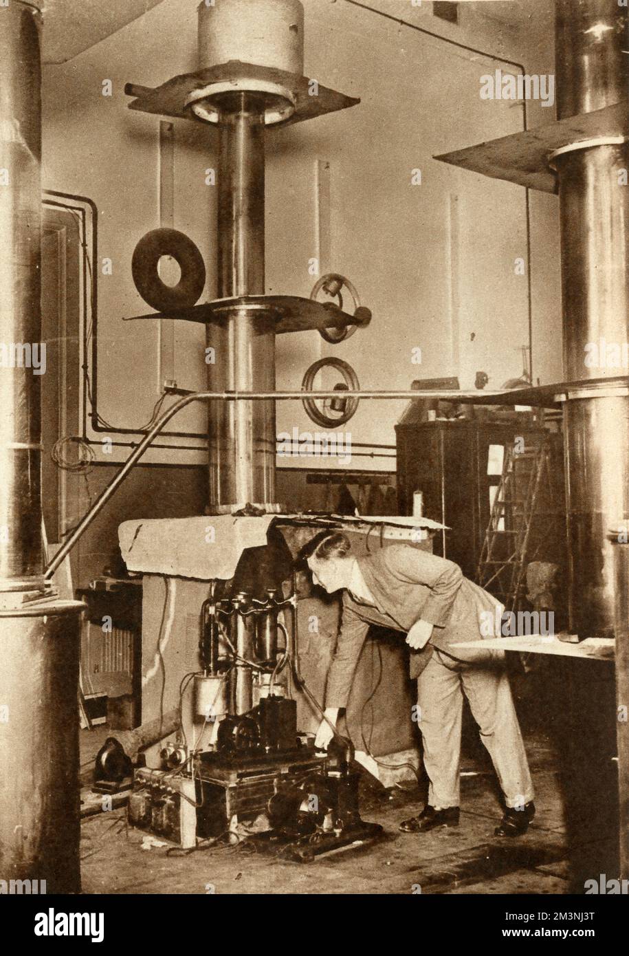 El Dr. J D Cockcroft trabaja en el Laboratorio Cavendish, en la Universidad de Cambridge, ajustando una bomba que genera vacío. Los físicos John D Cockcroft y Ernest T S Walton desarrollaron el acelerador Cockcroft-Walton para acelerar artificialmente las partículas atómicas a altas energías. Los protones de movimiento rápido hechos de hidrógeno fueron dirigidos hacia un blanco de litio en un vacío, y se observaron los resultados de esta división de átomos. Fecha: 1932 Foto de stock