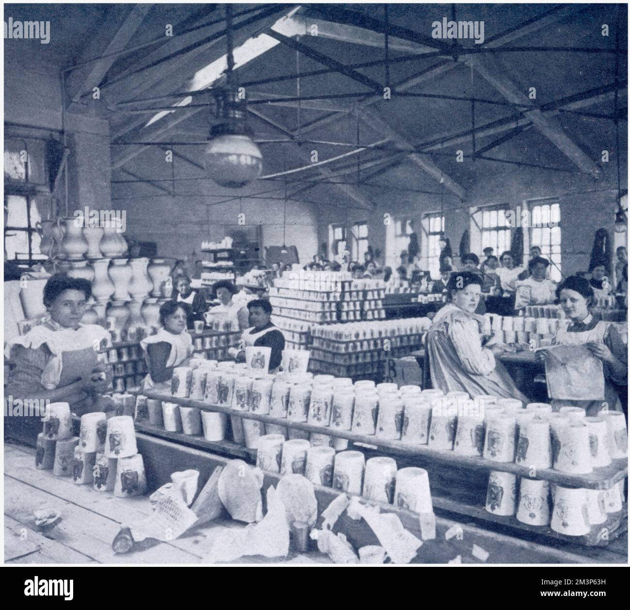 Mujeres en las alfarerías reales de Doulton en Burslem, fotografiaron la decoración y el acristalamiento de los vasos de precipitados de la coronación para conmemorar la coronación del rey Jorge V en 1911 y se entregaron a 100.000 niños en la fiesta del Palacio de Cristal el 30 de junio de ese año. Foto de stock