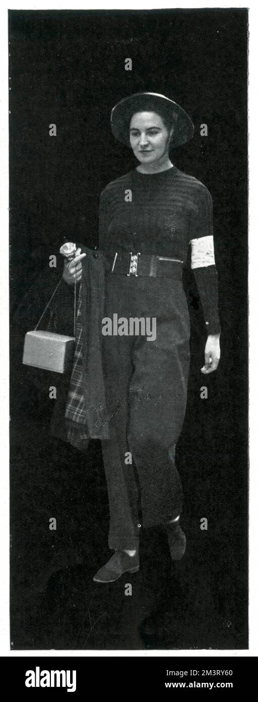 Una trabajadora de ambulancia fotografiada mientras viaja a Londres, unas semanas después de la Segunda Guerra Mundial. Además de uniforme, este trabajador de ambulancia lleva su máscara de gas y linterna. Fecha: 1939 Foto de stock