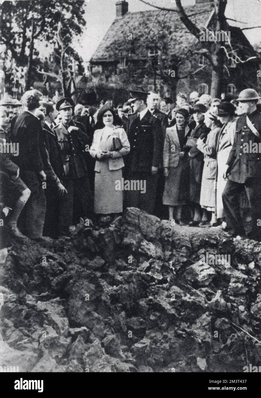El rey Jorge VI y la reina Isabel observan una batalla aérea mientras visitan las zonas bombardeadas de Londres. Están de pie en el borde de un gran cráter. Foto de stock