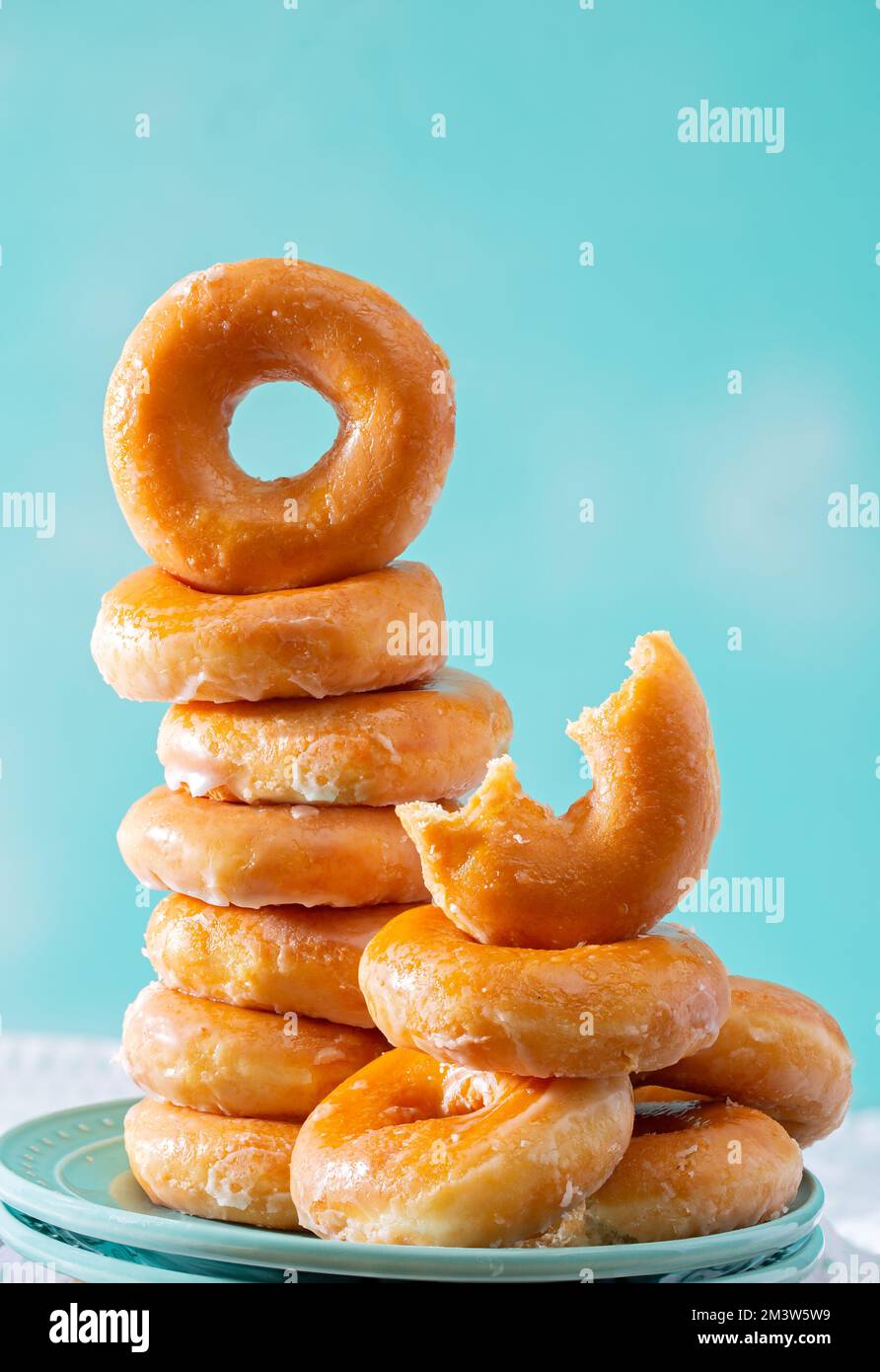 Pila de donuts esmaltados sobre un fondo de color aqua con espacio de copia Foto de stock