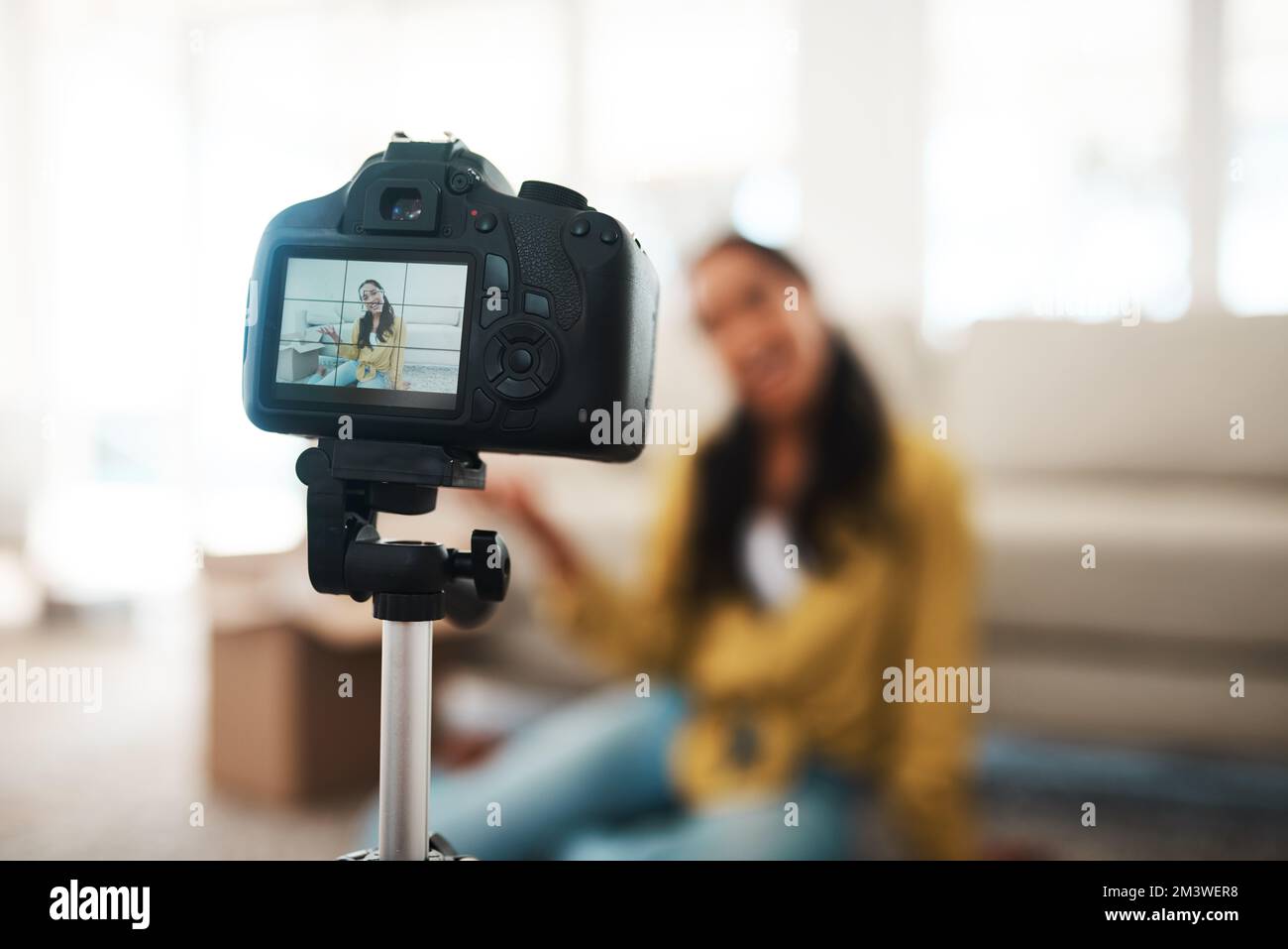 Bienvenido a la era digital. una atractiva joven empresaria sentada en su sala de estar y usando su cámara para grabar su vlog. Foto de stock