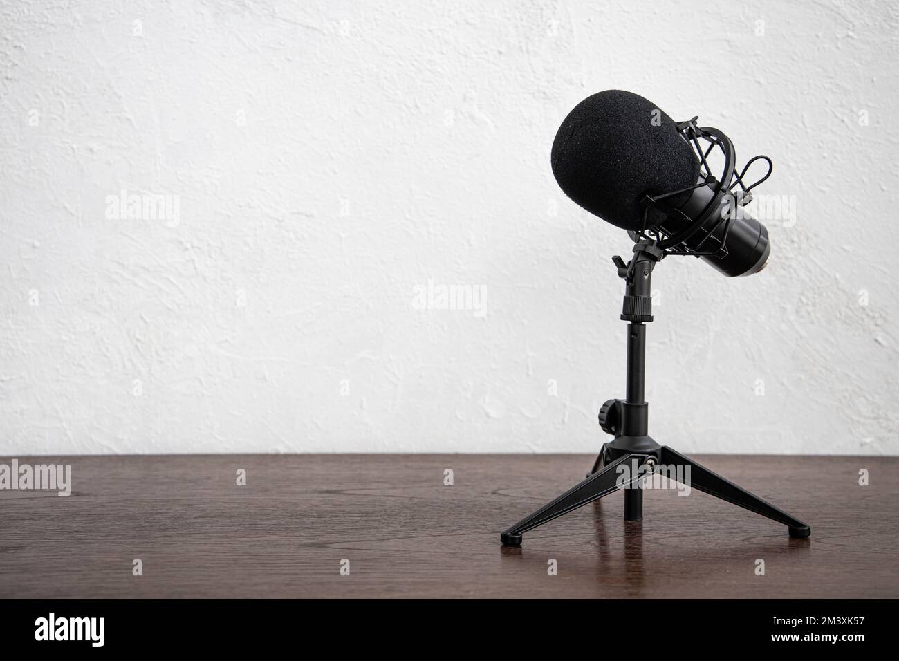 Micrófono de condensador de estudio para el podcast de radio de estudio  casero aislado en el espacio de fondo de mesa de madera de pared blanca  para texto Fotografía de stock -