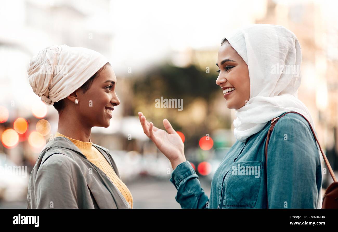¿Qué cree que deberíamos hacer a continuación? una atractiva mujer joven con un hijab y hablando con su amiga mientras recorre la ciudad. Foto de stock