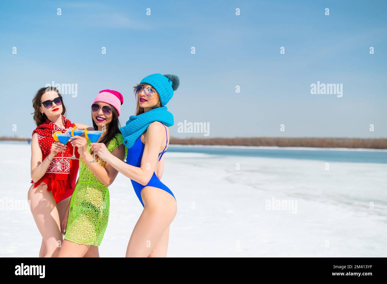 Tres amigas en bañadores beben cócteles alcohólicos azules en una playa  nevada. Chicas calientes posando en bikinis al aire libre en invierno  Fotografía de stock - Alamy