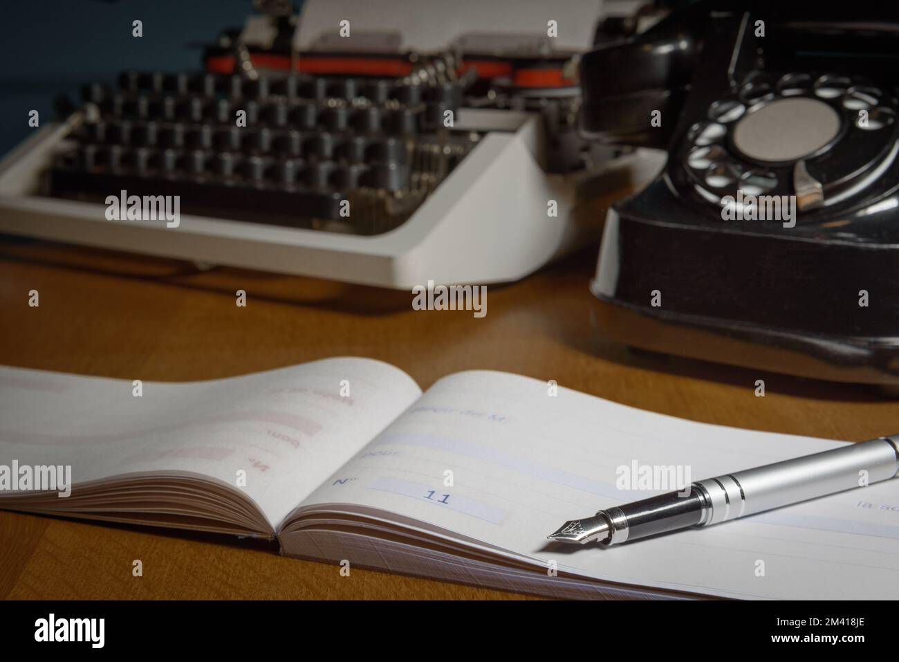 Chequera, pluma de tinta, máquina de escribir retro y teléfono viejo en la mesa. . Enfoque seleccionado Foto de stock