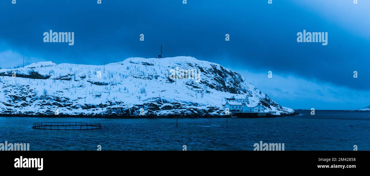 Edificios en la colina cubierta de nieve con nubes oscuras, Noruega Foto de stock