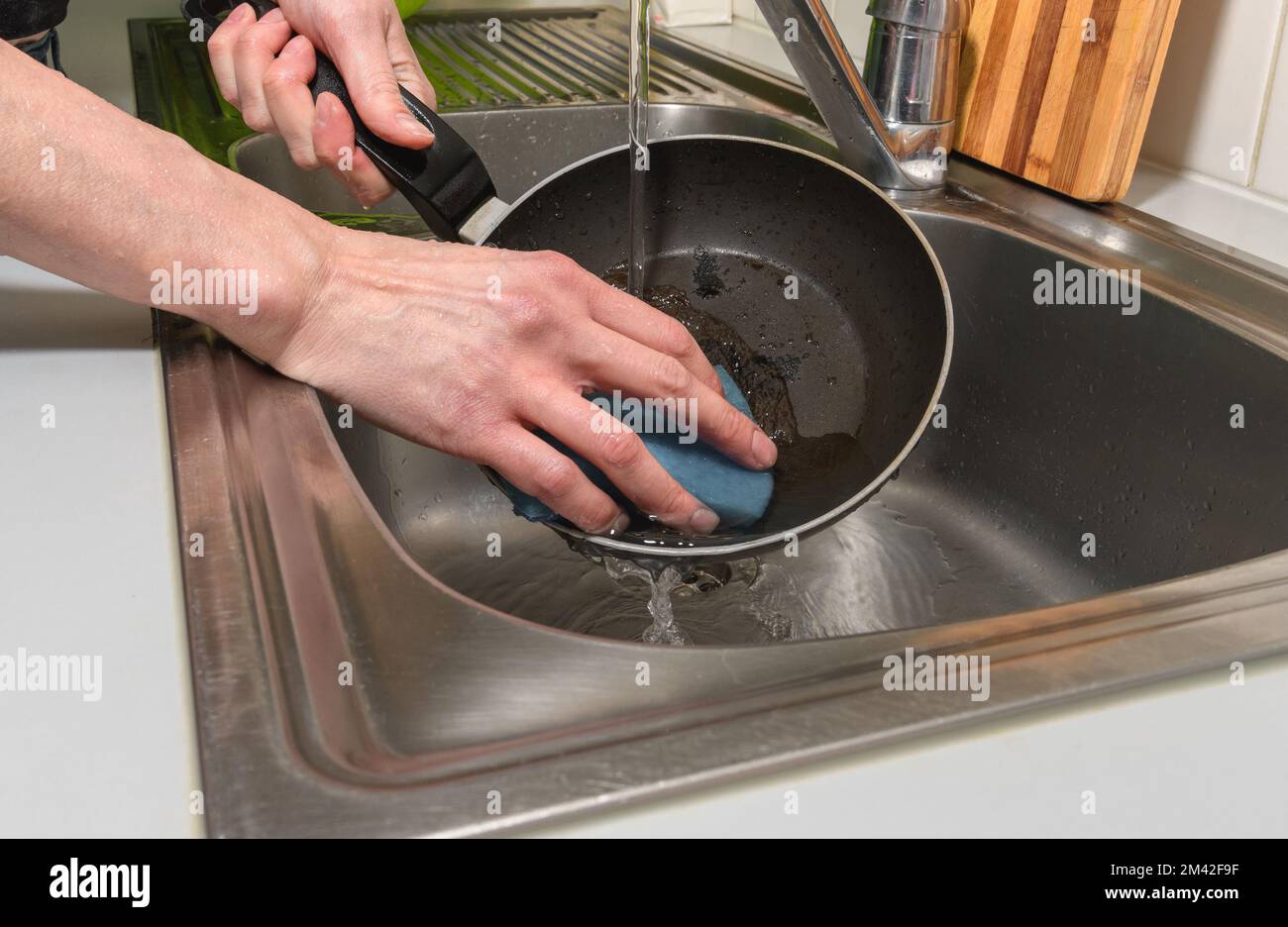 https://c8.alamy.com/compes/2m42f9f/una-mujer-trata-de-limpiar-una-sarten-quemada-con-sus-manos-y-una-esponja-para-lavar-platos-2m42f9f.jpg