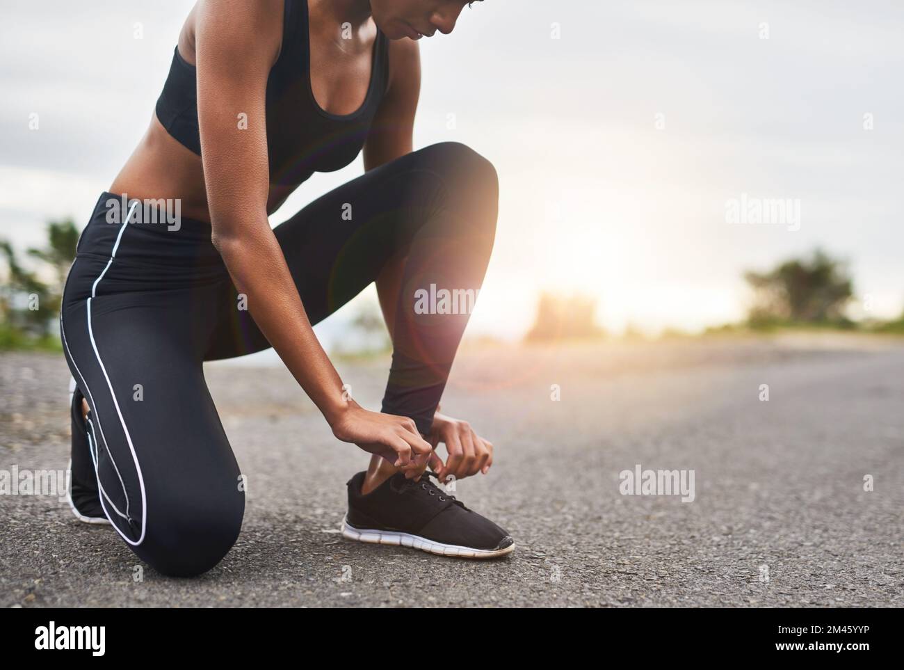 Lo lograrás hasta el final Primer plano de una mujer deportiva atando sus cordones mientras hace ejercicio al aire libre. Foto de stock