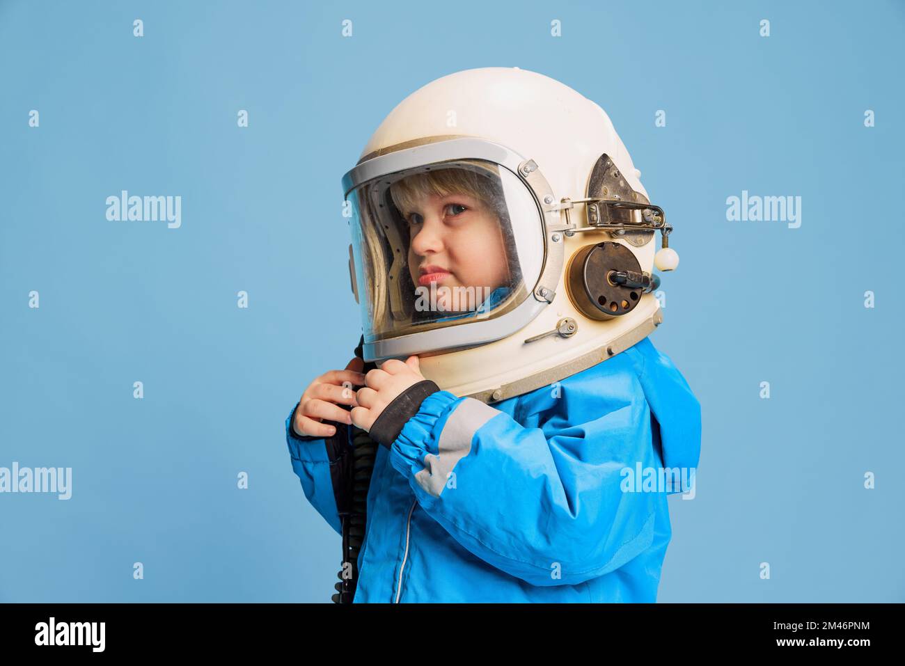Retrato de niño pequeño, niño posando en traje de astronauta, casco sobre  fondo azul de estudio. Parece descontento Fotografía de stock - Alamy