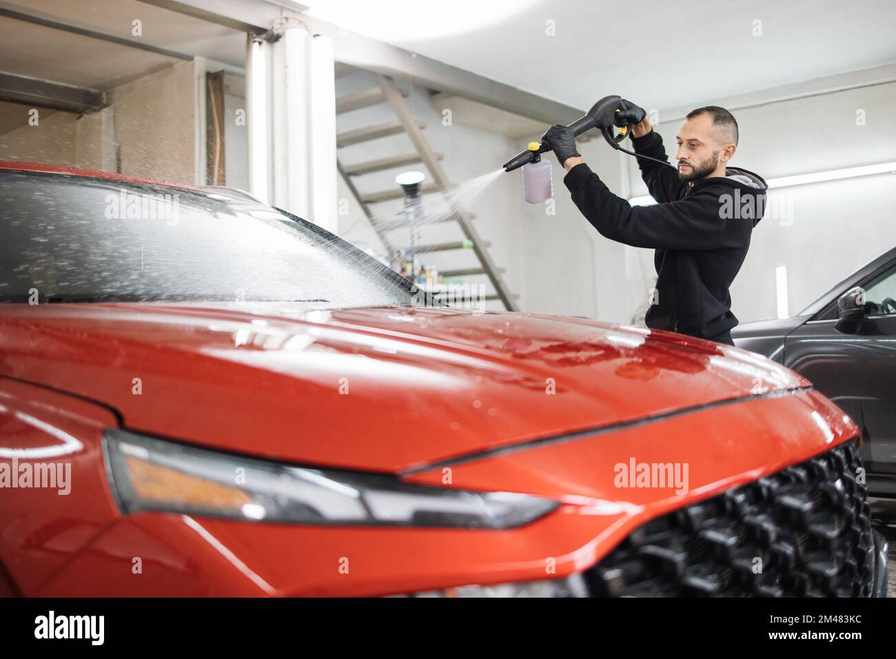 Primer plano horizontal de coche negro con espuma de limpieza en el  servicio de lavado de