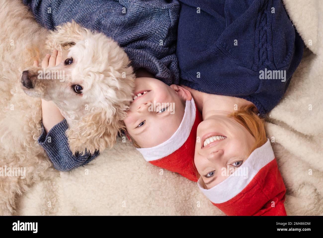 Independientemente Perseguir mano Una mujer con un hijo pequeño y un perro vestido con sombreros de Año Nuevo  está acostada en el sofá y sonriendo. Vista desde arriba Fotografía de  stock - Alamy