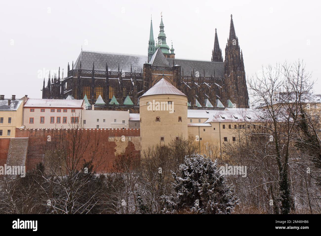 Ciervo Moat y Mihulka torre en primer plano con techos de St. Vitus cas, con techos cubiertos de nieve del Castillo de Praga en invierno Foto de stock