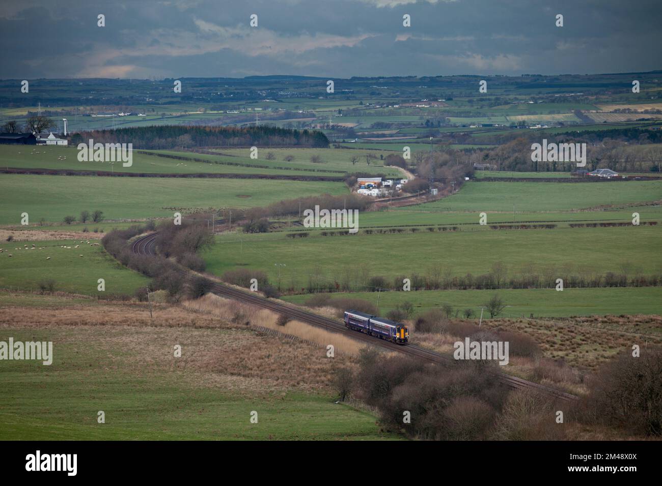Tren Scotrail clase 156 en la pintoresca Glasgow rural y la línea suroeste en Ayrshire, Escocia pasando Mossgiel Foto de stock