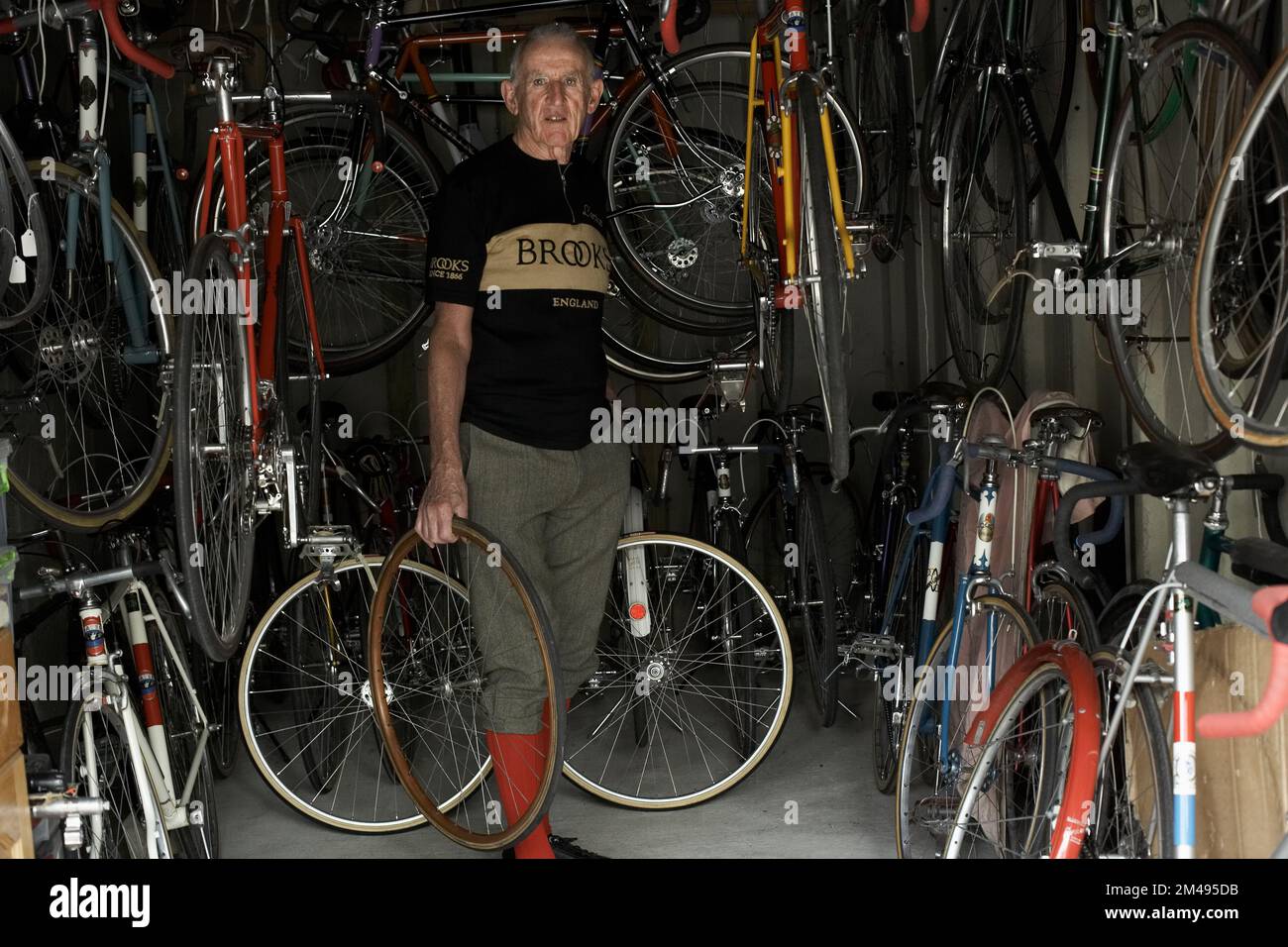 Hombre maduro que sostiene dos ruedas de bicicleta en un garaje. Foto de stock
