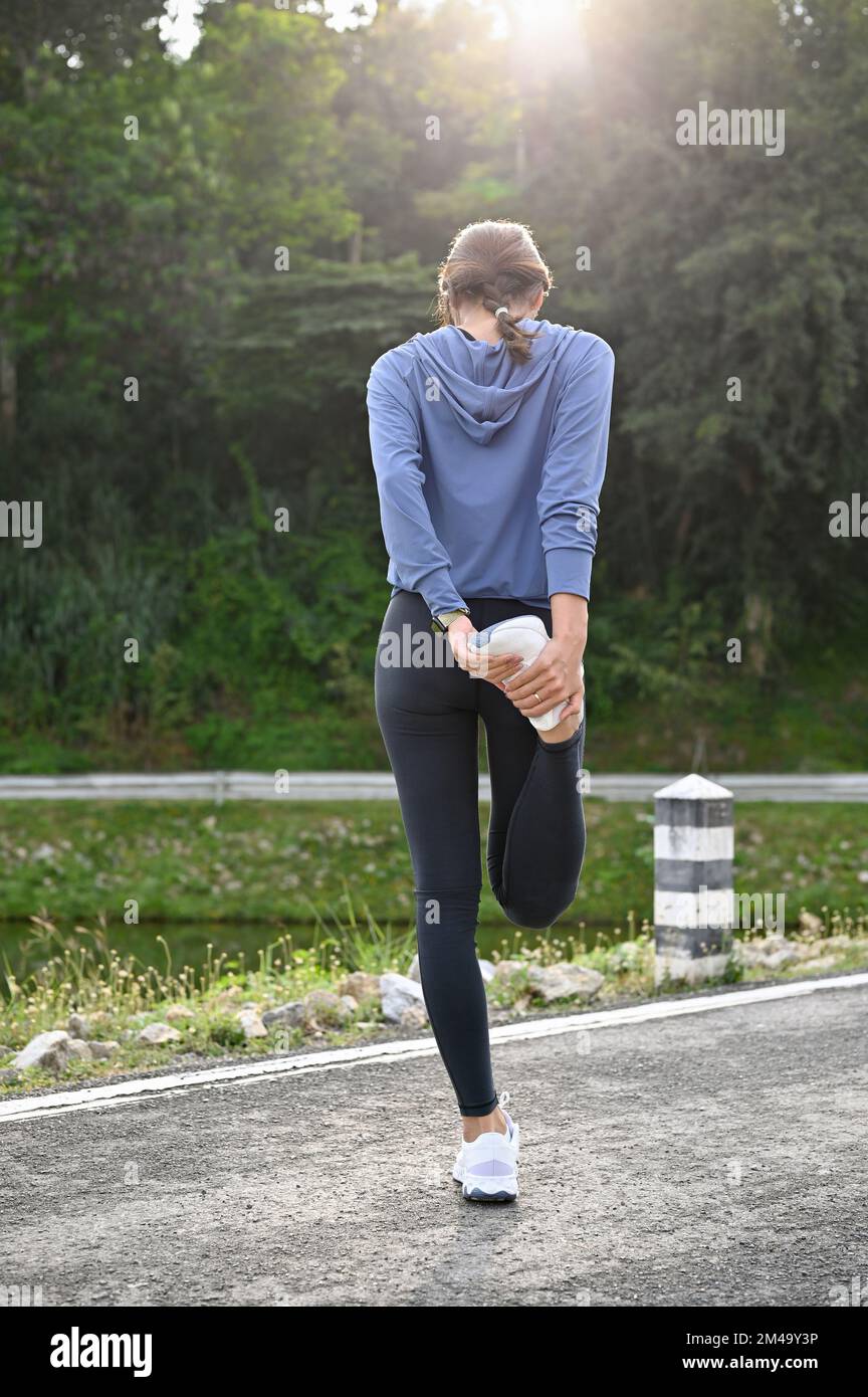 Vista trasera, Una mujer asiática sana en ropa deportiva estirando
