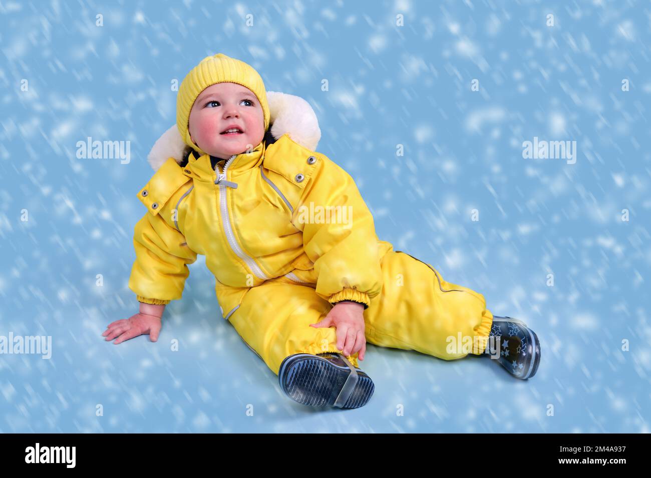Los bebés pequeños en un mono rojo posando sentada en la nieve Fotografía  de stock - Alamy