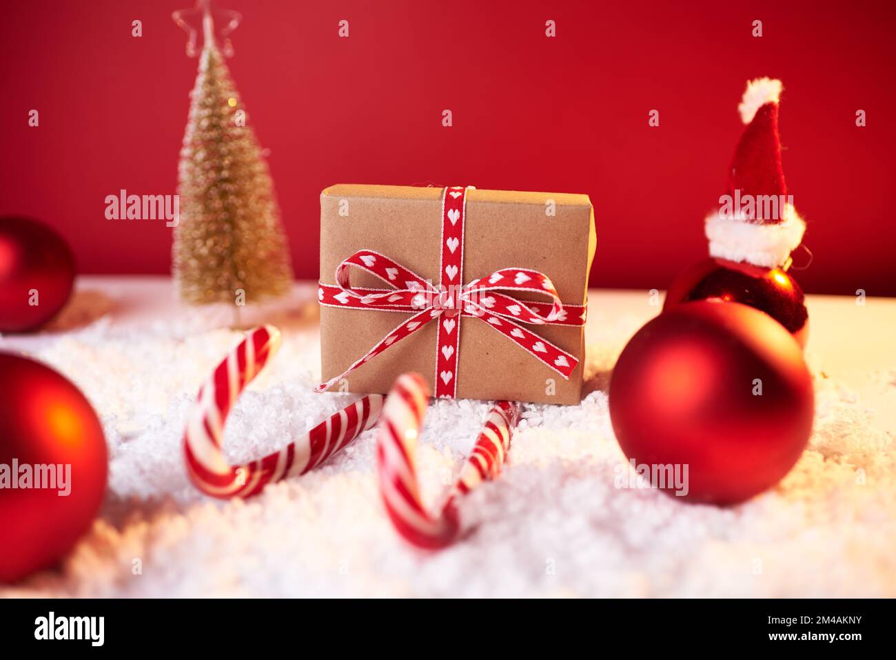 Concepto de Navidad, trineo de Santa de regalo rojo y bastones de caramelo sobre fondo rojo, regalo para las vacaciones de invierno, espacio de copia. Foto de stock