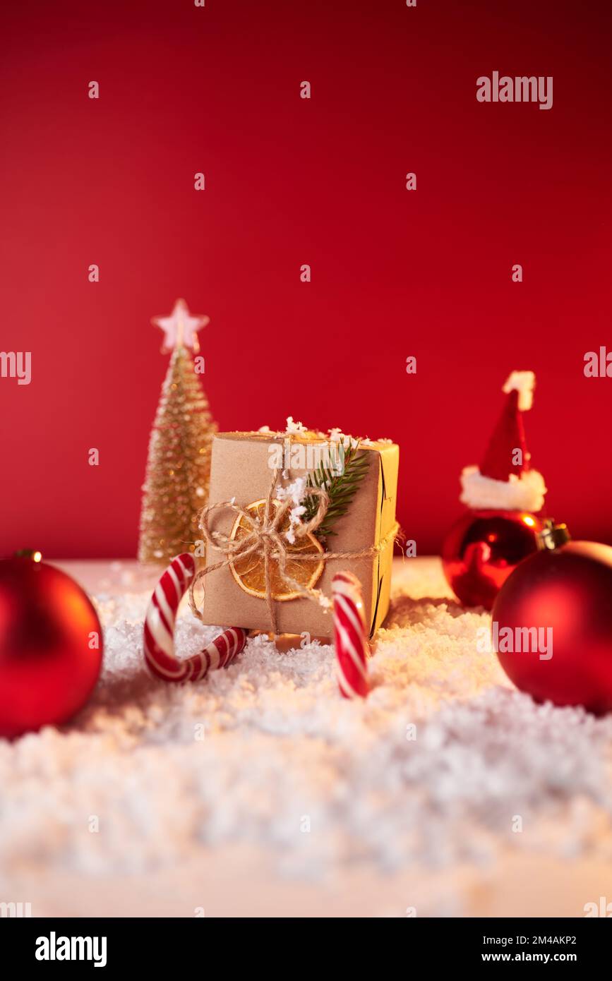Concepto de Navidad, trineo de Santa de regalo rojo y bastones de caramelo sobre fondo rojo, regalo para las vacaciones de invierno, espacio de copia. Foto de stock