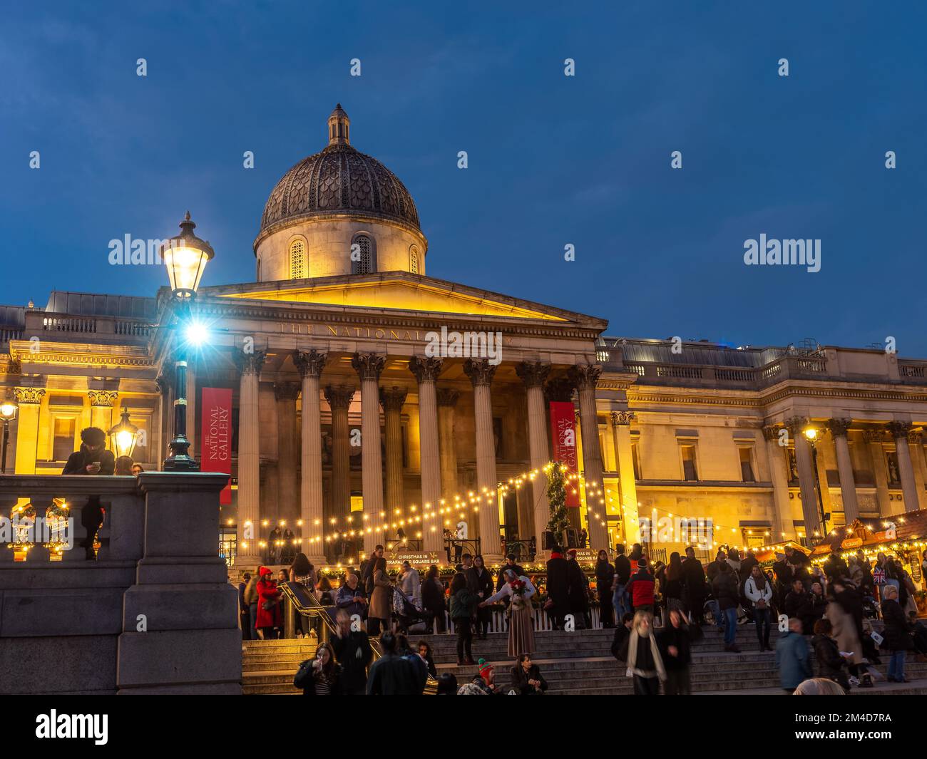 Londres, Inglaterra, Reino Unido - 20 de diciembre de 2022: Mercado de Navidad al aire libre con gente disfrutando de las vacaciones de invierno frente al edificio de la Galería Nacional Foto de stock