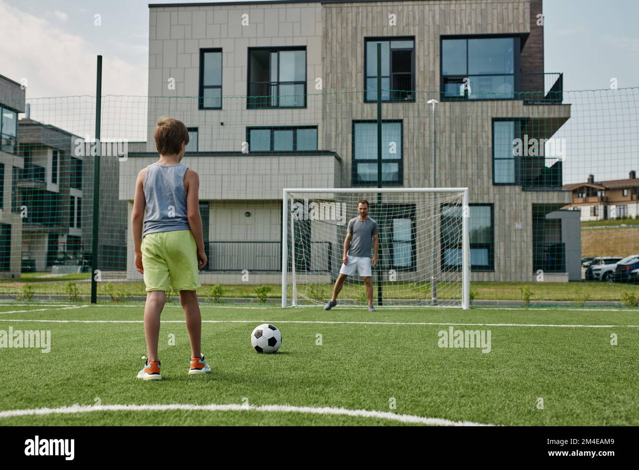 Vista posterior del muchacho adolescente que juega al fútbol con el padre que se coloca en las puertas, espacio de la copia Foto de stock