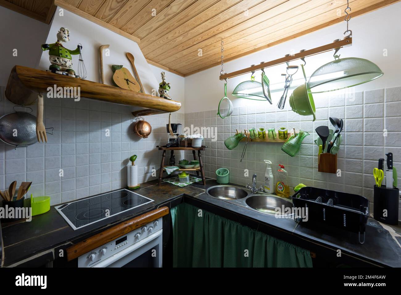 Pequeña cocina retro de la casa rústica con azulejos blancos y techo de madera Foto de stock
