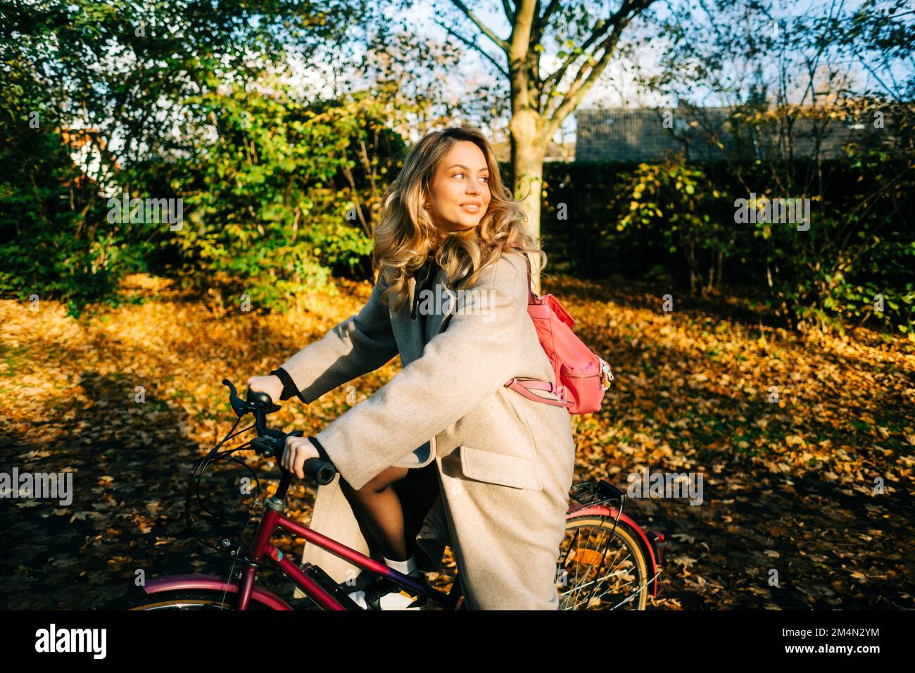 Joven mujer caucásica atractiva paseo en bicicleta en el parque en día cálido en el otoño. Foto de stock