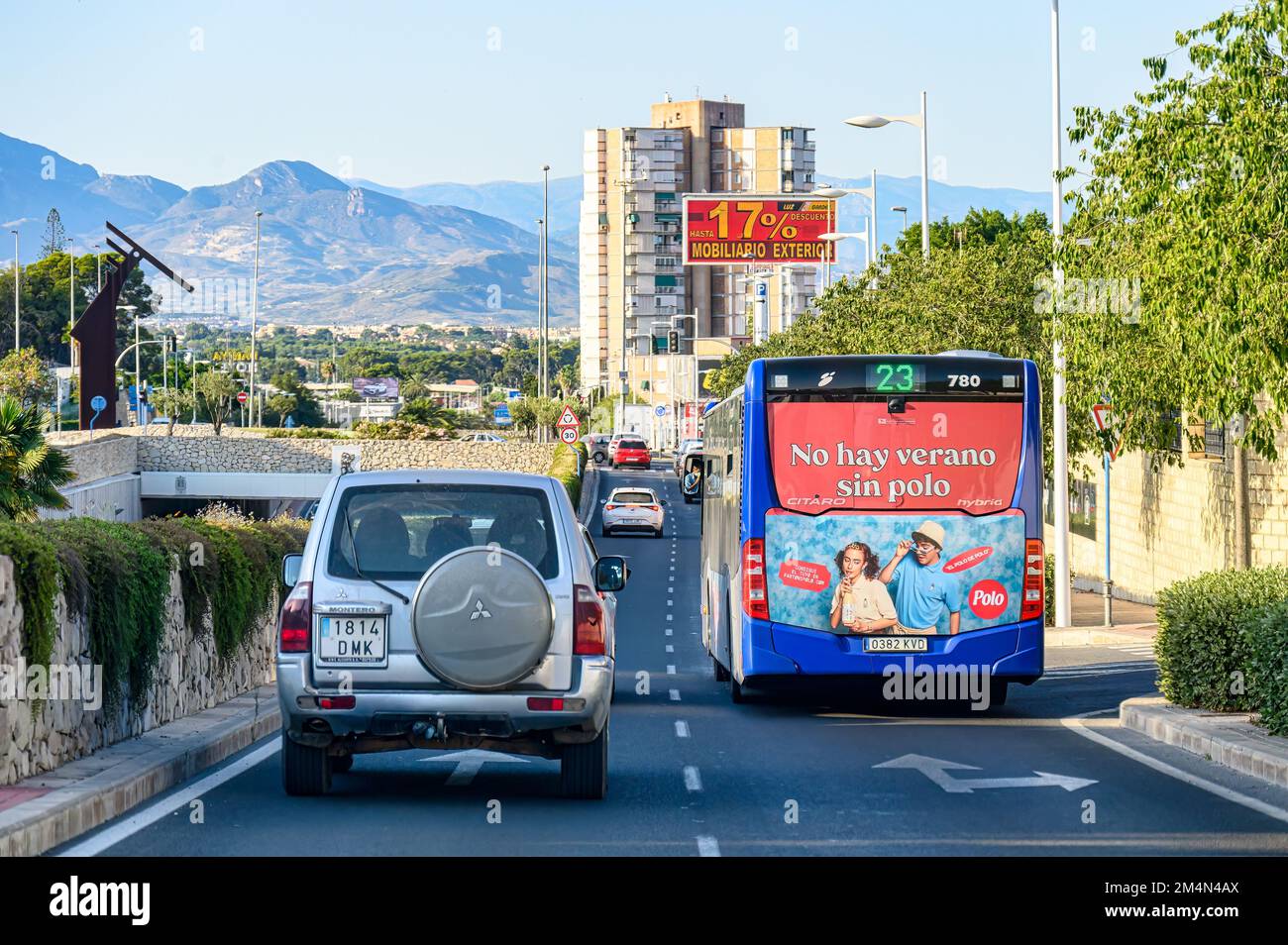 Un coche conduce junto al autobús de la ruta 23. El vehículo de pasajeros pertenece al sistema de transporte público de la ciudad de Alicante. Foto de stock