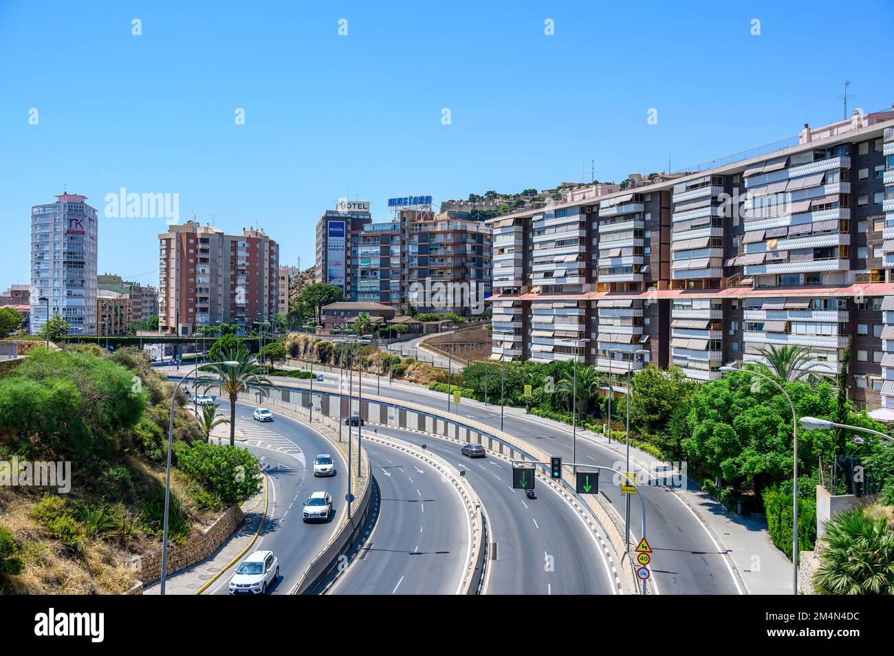 Vista aérea de una carretera o avenida urbana de la ciudad de Alicante. Un grupo de coches conducen por los edificios de apartamentos en el lado. Foto de stock
