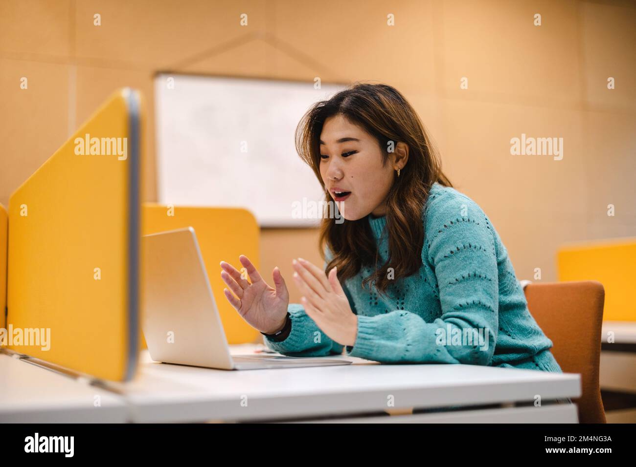 Estudiante femenina que trabaja en la computadora portátil en un cubículo de la biblioteca Foto de stock
