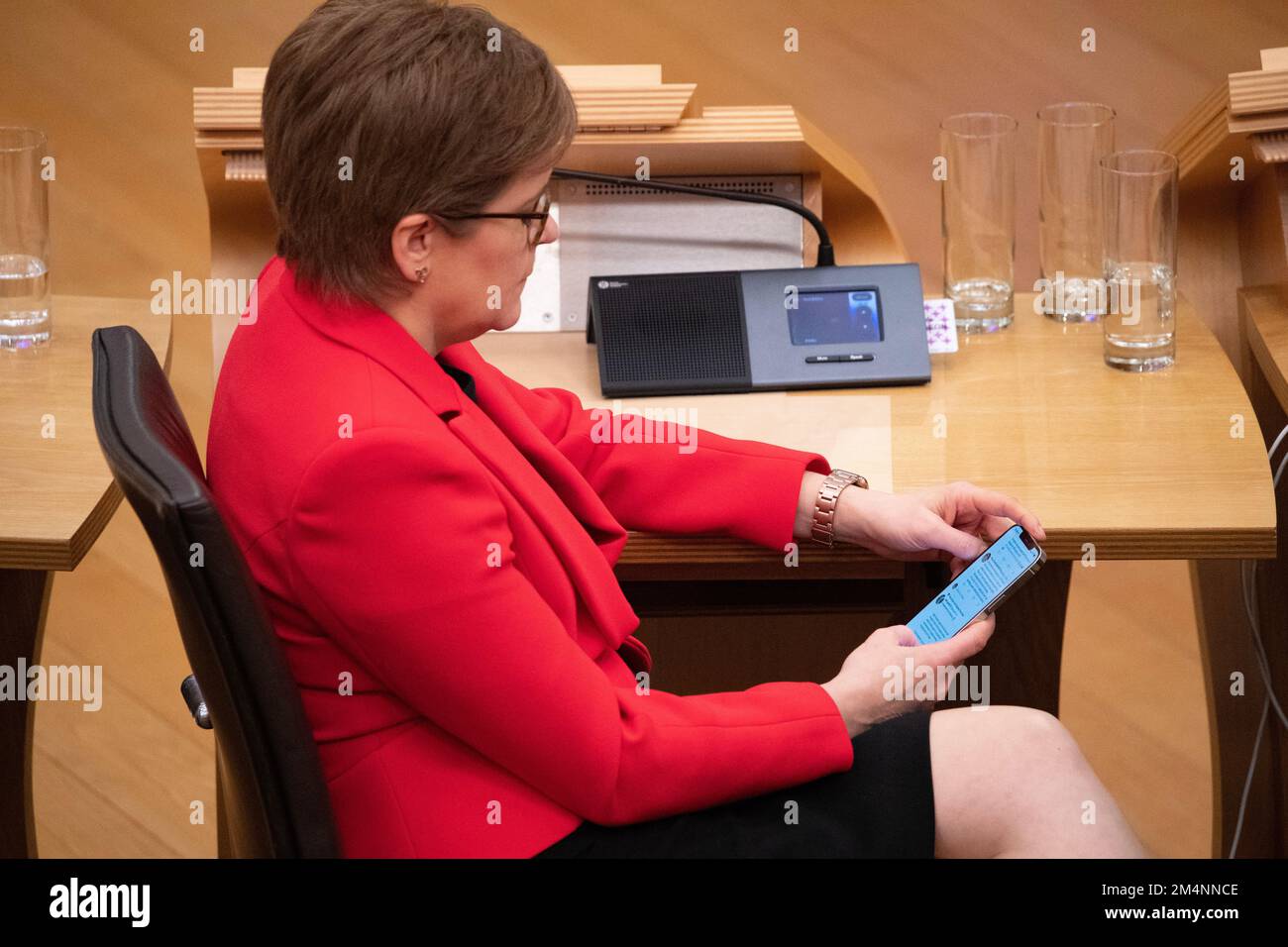 Edimburgo, Escocia, Reino Unido. 22nd de diciembre de 2022. EN LA FOTO: Nicola Sturgeon MSP, Primera Ministra de Escocia, revisa su teléfono móvil para ver las reacciones de las redes sociales a la aprobación del proyecto de ley. Reacciones dentro de la cámara de debate después de que el proyecto de ley de la etapa 3 apruebe el proyecto de ley de Reforma de Reconocimiento de Género (Escocia), donde las personas que buscan obtener un Certificado de Reconocimiento de Género (GRC) con identificación personal, no necesitan obtener ningún informe médico para obtener su GRC. Crédito: Colin D Fisher Crédito: Colin Fisher/Alamy Live News Foto de stock
