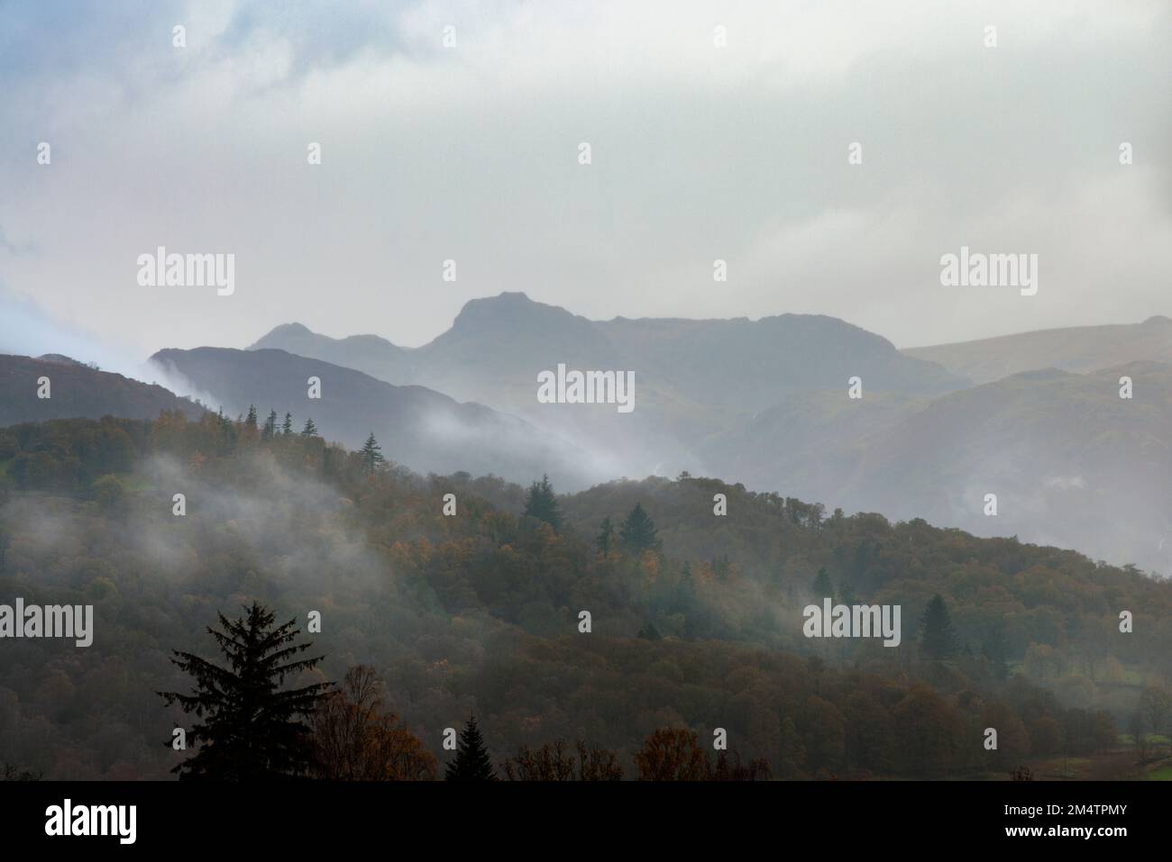 Niebla de la mañana y los Langdale Pikes. Foto de stock