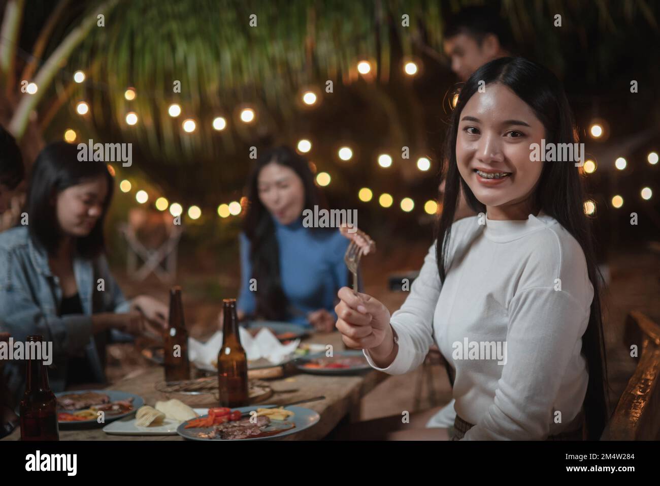 Mujer joven asiática mostrando comer bistec en una fiesta Foto de stock